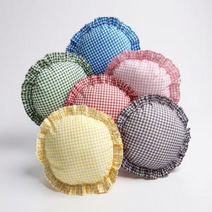 Può includere: Una collezione di sei cuscini rotondi in vari colori, tra cui blu, verde, rosso, rosa, giallo e grigio. Ogni cuscino presenta un motivo a quadretti e un bordo a balze. I cuscini sono disposti in modo leggermente sovrapposto.