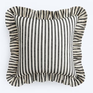 May include: Square decorative pillow with a black and off-white vertical stripe pattern. The pillow has a ruffled border in a matching black and off-white striped fabric, creating a textured and stylish look. The pillow is designed for home decor.