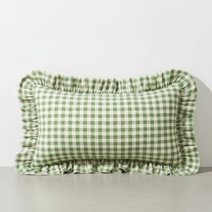 May include: A rectangular decorative pillow with a green and white gingham pattern. The pillow has a ruffled edge, adding a touch of elegance. The pillow is designed for home decor.