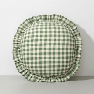 May include: Round cushion with a green and white gingham pattern and a ruffled border. This decorative cushion is suitable for a bed or sofa. The cushion's diameter is approximately 40 cm.