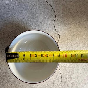 Peut inclure: Un bol en c&eacute;ramique blanc avec un bord marron est mesur&eacute; avec un m&egrave;tre ruban jaune. Le bol mesure environ 12.7 cm de diam&egrave;tre. Le m&egrave;tre ruban affiche des mesures en cm et en pouces.