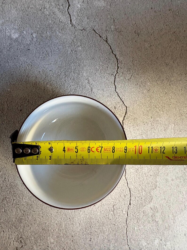 Peut inclure: Un bol en c&eacute;ramique blanc avec un bord marron est mesur&eacute; avec un m&egrave;tre ruban jaune. Le bol mesure environ 12.7 cm de diam&egrave;tre. Le m&egrave;tre ruban affiche des mesures en cm et en pouces.