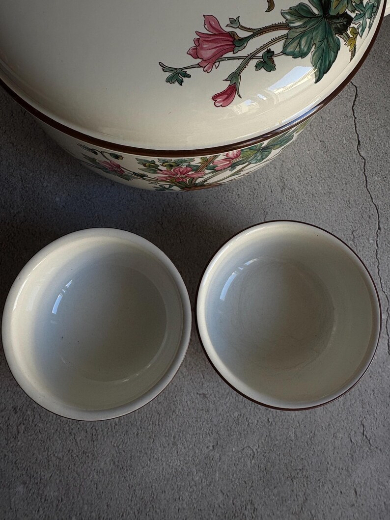 Peut inclure: Un grand bol de service en c&eacute;ramique cr&egrave;me avec un motif floral rose et vert, et deux petits bols assortis. Les bols ont une bordure marron fonc&eacute;. Le motif floral est sur le couvercle du bol.