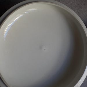 Peut inclure: Un couvercle en c&eacute;ramique de couleur cr&egrave;me avec un bord l&eacute;g&egrave;rement sur&eacute;lev&eacute;. Le couvercle a une surface lisse et brillante avec un petit trou au centre. Le couvercle est con&ccedil;u pour s'adapter &agrave; un plat ou une casserole rond.