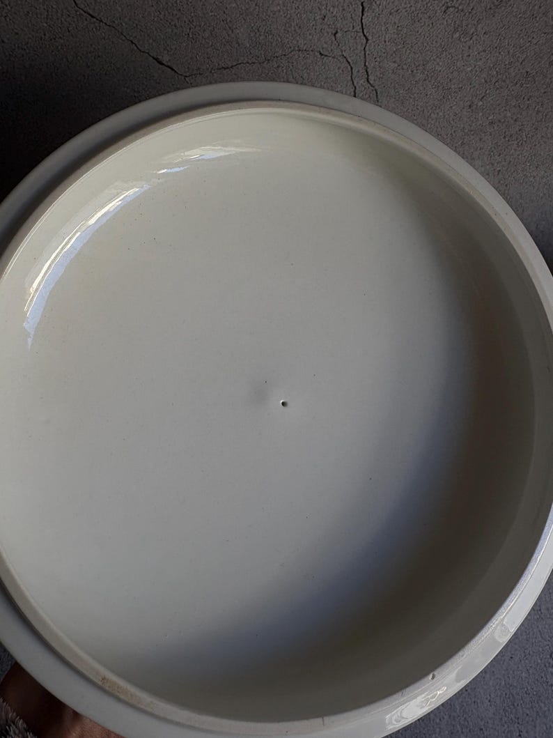 Peut inclure: Un couvercle en c&eacute;ramique de couleur cr&egrave;me avec un bord l&eacute;g&egrave;rement sur&eacute;lev&eacute;. Le couvercle a une surface lisse et brillante avec un petit trou au centre. Le couvercle est con&ccedil;u pour s'adapter &agrave; un plat ou une casserole rond.