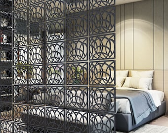 May include: A black room divider made of wood with a geometric pattern. The divider is made up of multiple panels that can be arranged in different ways. The divider is shown in front of a bed with white bedding and pillows.