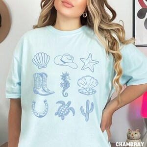 woman wearing a chambray shirt with rows of cowgirl and coastal elements.