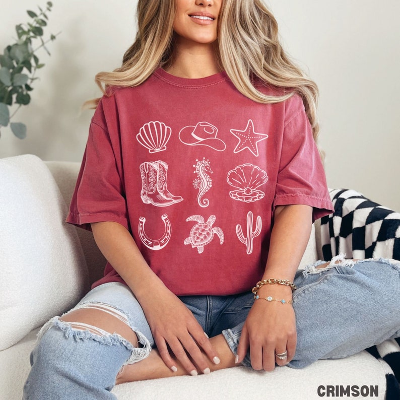 woman wearing a crimson shirt with rows of cowgirl and coastal elements.