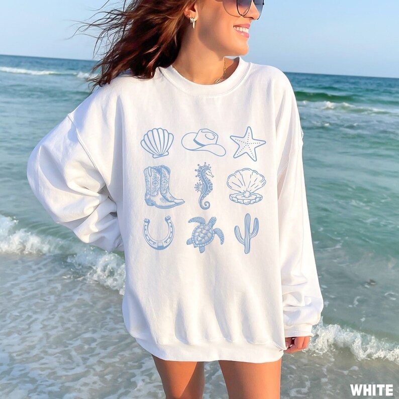 woman wearing the white sweatshirt with rows of western and ocean elements in blue design.