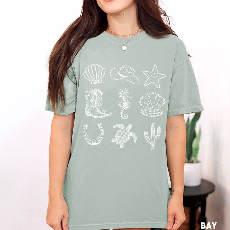 woman wearing a bay shirt with rows of cowgirl and coastal elements.