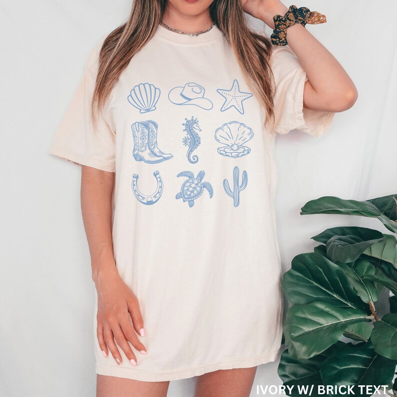 woman wearing an ivory shirt with rows of cowgirl and coastal elements.