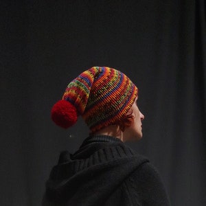 Slouchy colorful beanie with one red pom pom.