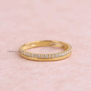 Könnte beinhalten: Ein dünner Goldring mit einer Reihe kleiner, klarer Diamanten, die die Band umschließen.