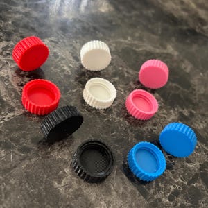 May include: Assortment of ten plastic bottle caps in various colors, including red, white, pink, black, and blue.