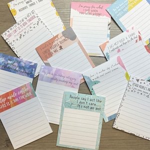 May include: A set of colorful notepads with humorous and motivational quotes. The notepads have lined paper and are perfect for writing down thoughts, ideas, or to-do lists.