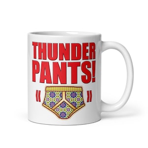 Op de afbeelding: Witte keramische mok met de tekst "THUNDER PANTS!" in rode letters en een kleurrijke ondergoedgrafiek.