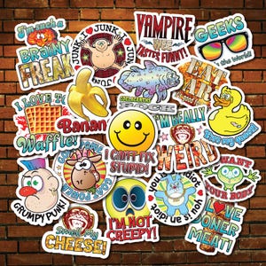 May include: A selection of vibrant stickers featuring diverse designs and text, such as a smiley face, a banana, and the phrases "Brainy Freak" and "I Love To Waffle!". The stickers are displayed against a brick wall.