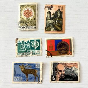 Könnte beinhalten: Eine Sammlung von fünf alten Briefmarken. Die Briefmarken zeigen verschiedene Motive, darunter ein Schloss, ein Hirsch, ein Porträt und sowjetische Symbole. Die Briefmarken sind in Grün-, Orange-, Blau- und Rottönen gehalten, mit kyrillischem Text.