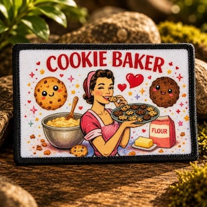 A rectangular patch with a black border featuring the text COOKIE BAKER in red. The illustration shows a person in a pink apron holding a tray of cookies, a mixing bowl with a wooden spoon, a bag of flour, butter, and two smiling cookies.