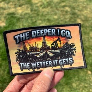 May include: A rectangular embroidered patch featuring a sunset background with oil rigs and pipelines. The text reads THE DEEPER I GO, THE WETTER IT GETS in bold, metallic-style lettering. The design includes black oil splashes and a thick black border.