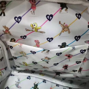 May include: White tote bag interior with a whimsical pattern of cartoon characters, hearts, and colorful lines. The lining features a pocket. The bag's interior is visible, showcasing the playful design.