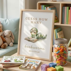 Puede incluir: Una impresión enmarcada con el texto "GUESS HOW MANY bookworms are in the jar" se encuentra sobre una mesa verde claro con libros infantiles y bloques de colores. Un tarro lleno de caramelos coloridos y un juguete de madera también están sobre la mesa. Un zorro y un conejo de peluche están en un asiento junto a la ventana.