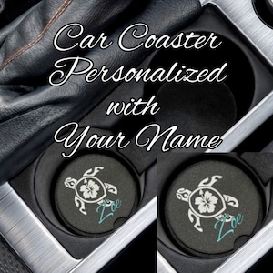 May include: Black car coasters with a turtle and hibiscus flower design, personalized with the name "Zoe" in teal. The coasters are in a car's cup holders, with the text "Car Coaster Personalized with Your Name" in white script.