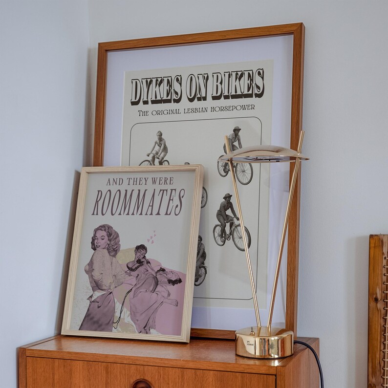 A framed print with two ladies in a romantic pose, with the text 'and they were roommates'.