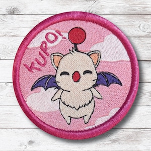 May include: Embroidered patch featuring a cartoon creature with a red nose, wings, and a red pom-pom. The patch is circular with a pink border and the word "KUPO!" in pink. The background has a pink and white cloud design.