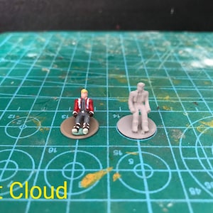 May include: Two miniature figures sitting on round bases. The figure on the left is wearing a red jacket, blue pants, and white shoes. The figure on the right is wearing a gray suit and black shoes. Both figures are painted in a realistic style.