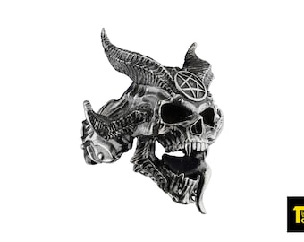 May include: A silver skull ring with horns and a pentagram on the forehead. The skull has a detailed design and a menacing expression.