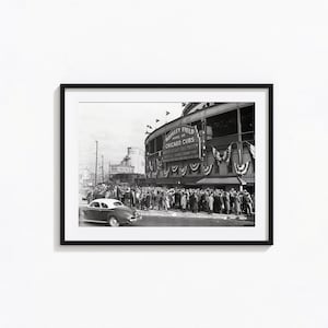 May include: A black and white photograph of a crowd of people gathered outside Wrigley Field, home of the Chicago Cubs. The sign above the entrance reads "Wrigley Field Home of the Chicago Cubs" and "Six Times National League Champions". A vintage car is parked in the foreground.