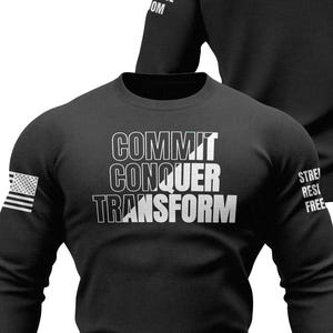 May include: Black long-sleeve sweatshirt with the words "COMMIT CONQUER TRANSFORM" in white block letters. An American flag is on the left sleeve. The back of the sweatshirt has a small graphic and the words "STRENGTH RESILIENCE FREEDOM".
