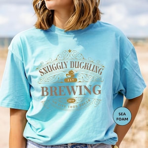 a woman standing on a beach wearing a blue shirt
