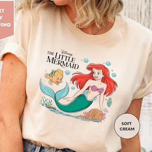 a woman wearing a t - shirt with the little mermaid on it