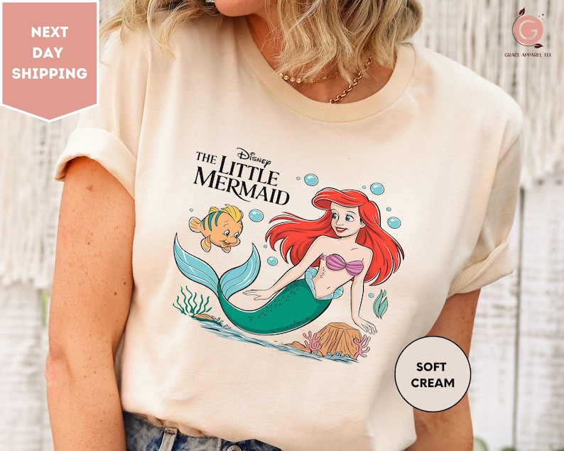 a woman wearing a t - shirt with the little mermaid on it