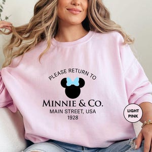 a woman sitting on a couch wearing a pink shirt