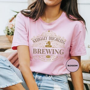 a woman wearing a pink t - shirt with a saying on it