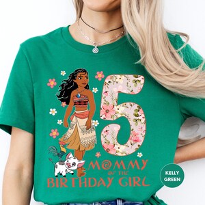 A green t-shirt with a graphic design featuring a cartoon character and the number 5, along with the text "MOMMY of the BIRTHDAY GIRL" and the text "KELLY GREEN" at the bottom.