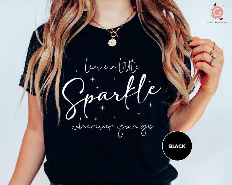 a woman wearing a black t - shirt that says leave a little sparkle wherever you