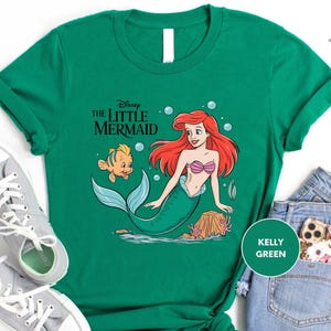 a green shirt with a little mermaid on it