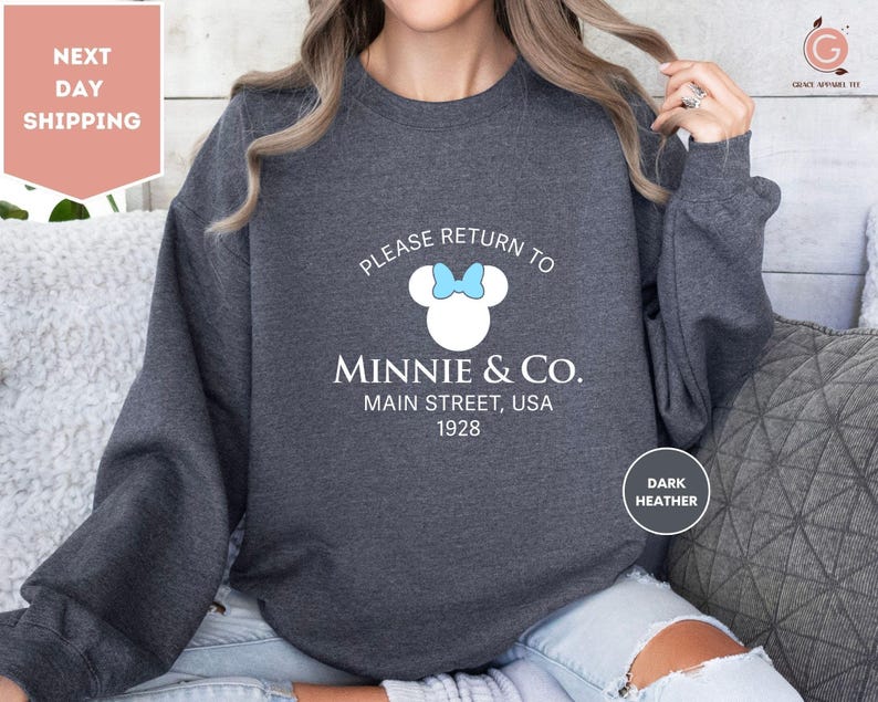 a woman wearing a sweatshirt that says please return to minnie & co main street,