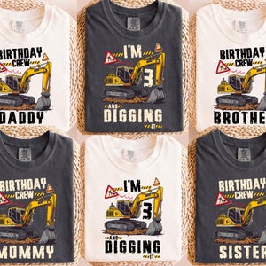 Op de afbeelding: Zes shirts met korte mouwen met graafmachine-ontwerpen. De shirts tonen een geelzwarte graafmachine met de tekst "BIRTHDAY CREW" en "DADDY", "BROTHER", "MOMMY" en "SISTER". Eén shirt zegt "I'M 3 AND DIGGING IT".