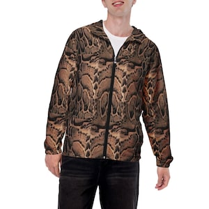 May include: A brown and black patterned jacket with a zipper closure and a hood. The jacket is worn by a person wearing black shorts and white sneakers.