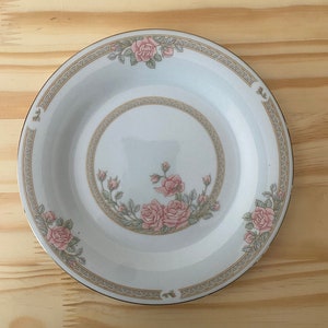 May include: A white ceramic plate with a gold rim and a floral design featuring pink roses and green leaves.