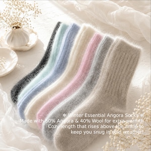 May include: A set of six fuzzy, ribbed socks in black, light blue, blue, cream, pink, and beige. The text on the image reads: Winter Essential Angora Socks, Made with 50% Angora & 40% Wool for extra warmth, Cozy length that rises above the ankle to keep you snug in cold weather!
