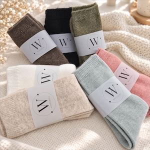 May include: A collection of seven pairs of folded socks in various colors including brown, black, olive green, white, beige, light blue, and pink. Each pair is secured with a white paper band featuring a circular logo with the letter W and the text WINTERING.