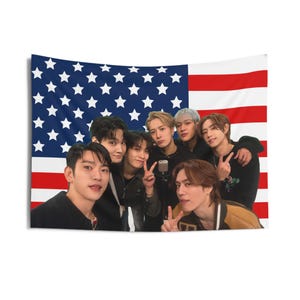 May include: Seven men stand in front of an American flag. They are all smiling and looking at the camera. The man in the centre is holding a microphone.