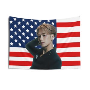 Könnte beinhalten: Ein Mann mit hellbraunen Haaren trägt einen schwarzen Blazer und posiert vor einer amerikanischen Flagge.