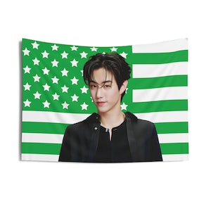 Op de afbeelding: Een zwart-groene Amerikaanse vlag met een man in een zwart shirt er voor.